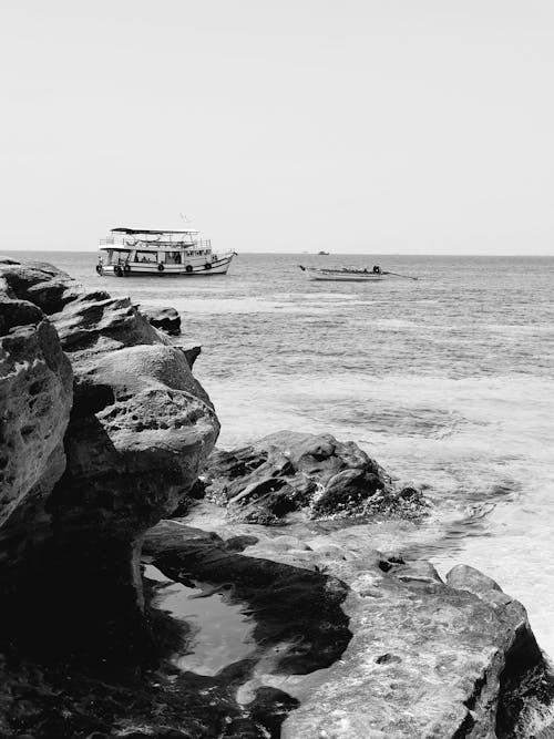 Black and White Photo of Cruise Ship at Sea and Rocky Coastline 