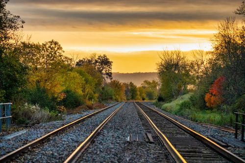 Free A beautiful view of railroad tracks surrounded by autumn trees in Minneiska, MN during golden hour. Stock Photo