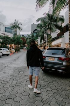 A man walks down a palm-lined street in Medellín, Colombia, blending nature and urban life.