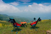 Two colorful camping chairs overlooking Vietnamese mountains under a bright blue sky.