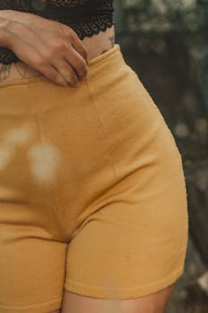 A woman's hand gently resting on yellow shorts, emphasizing texture and color contrast.