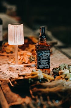 Jack Daniel's whiskey bottle elegantly displayed on a decorated dinner table with soft lamp lighting.