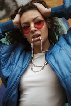 Stylish young woman posing confidently with bold fashion accessories and vibrant sunglasses.