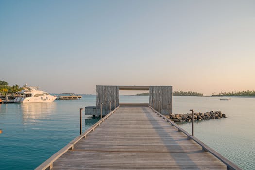 Tranquil scene of a wooden dock extending over calm blue waters with a yacht docked nearby, perfect for relaxation.