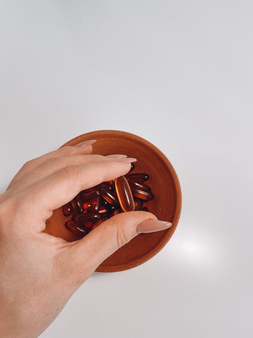 Woman Hand and Pills in Bowl