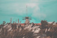 一座质朴的塔楼坐落在高高的草丛和树木之间，在蔚蓝天空的映衬下，户外场景显得格外宁静