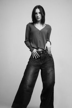 Black and white studio portrait of a stylish young woman in casual attire.