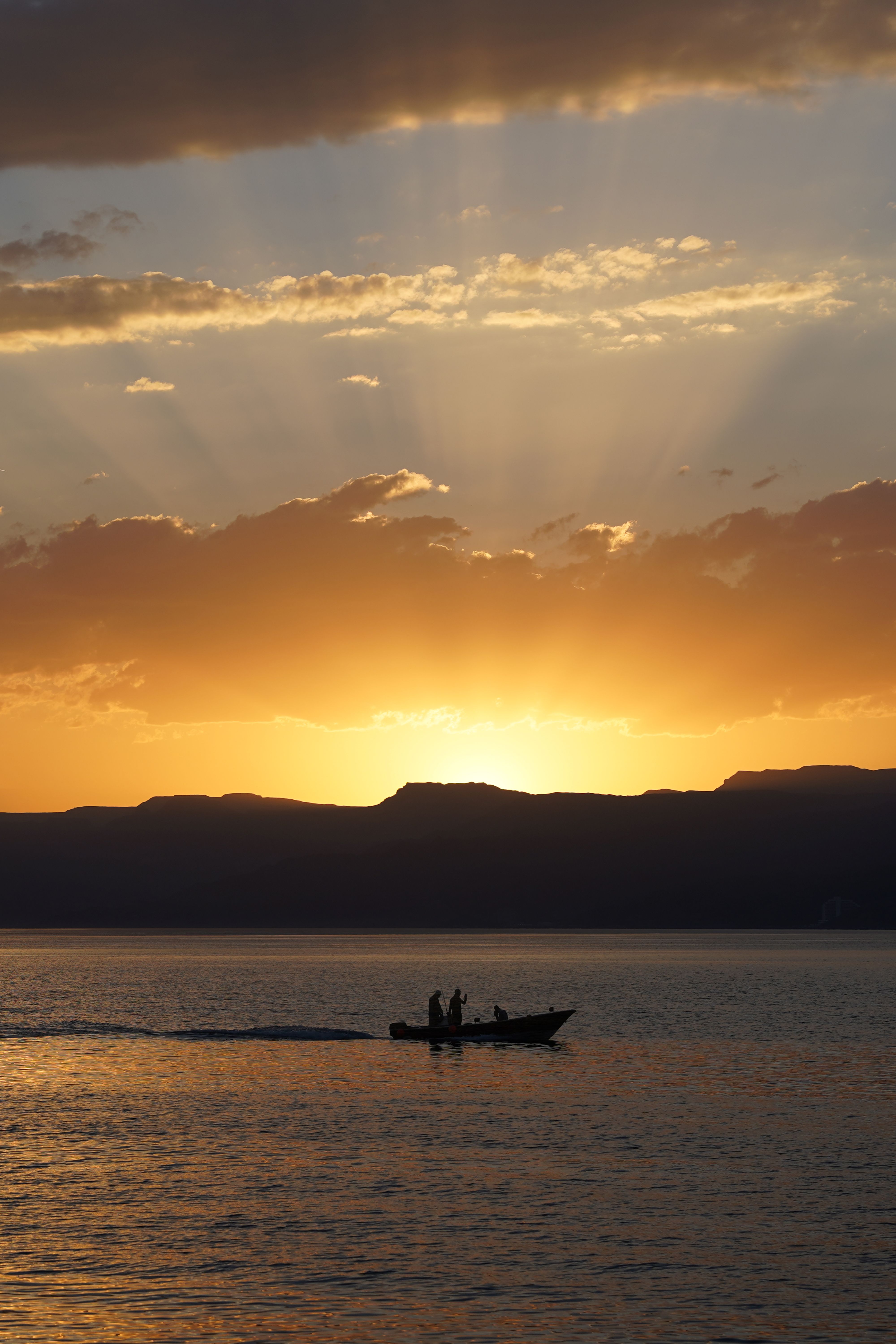 A tranquil scene of a silhouetted boat on the Red Sea at sunset, Aqaba, Jordan.