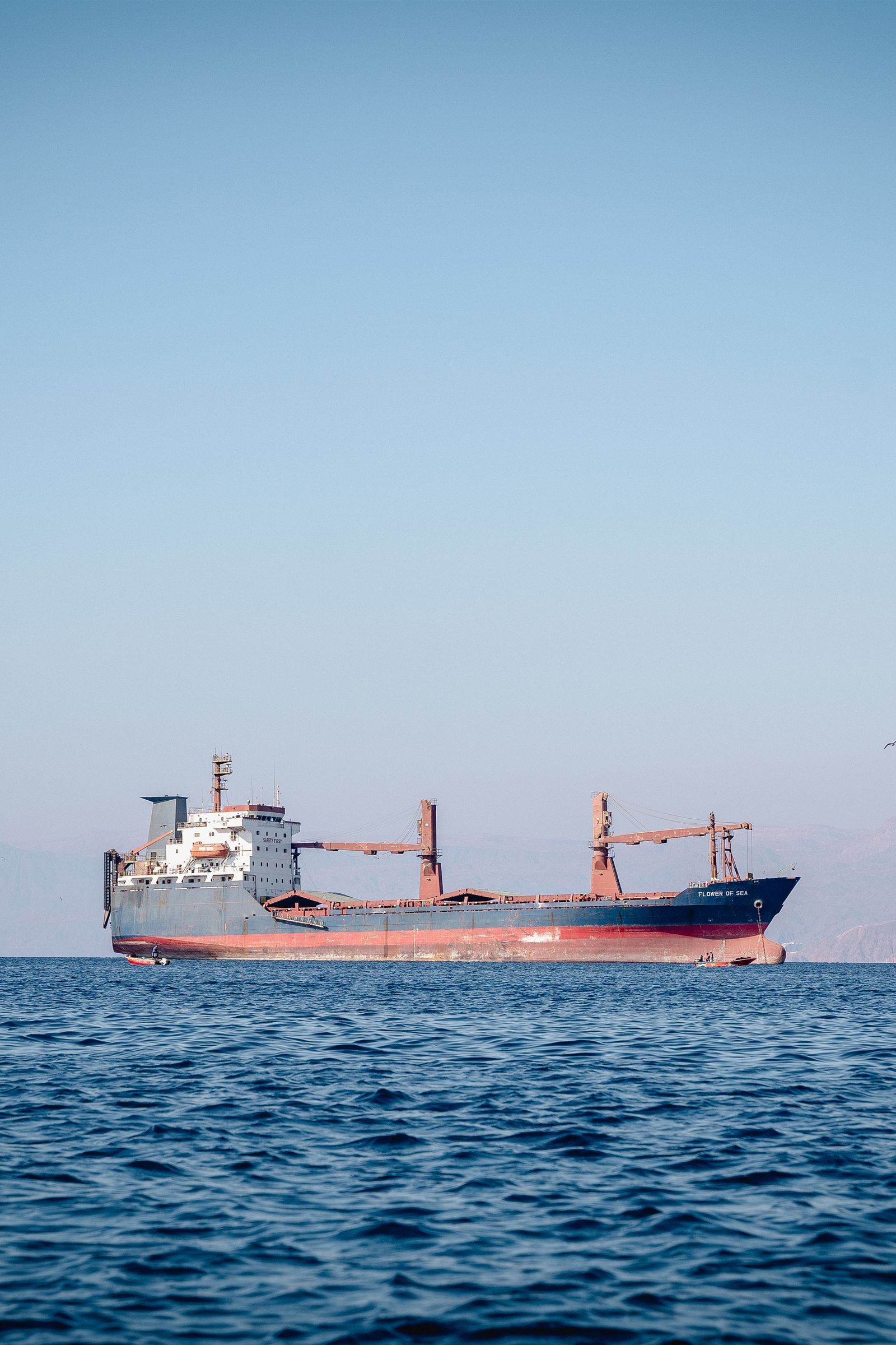 A cargo vessel sailing in the Gulf under blue sky.