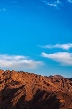 A breathtaking view of a rugged mountain range under a bright blue sky in Aqaba, Jordan.