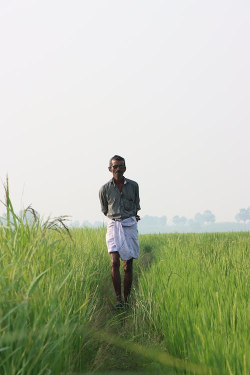 Man Walking on Footpath on Green Field