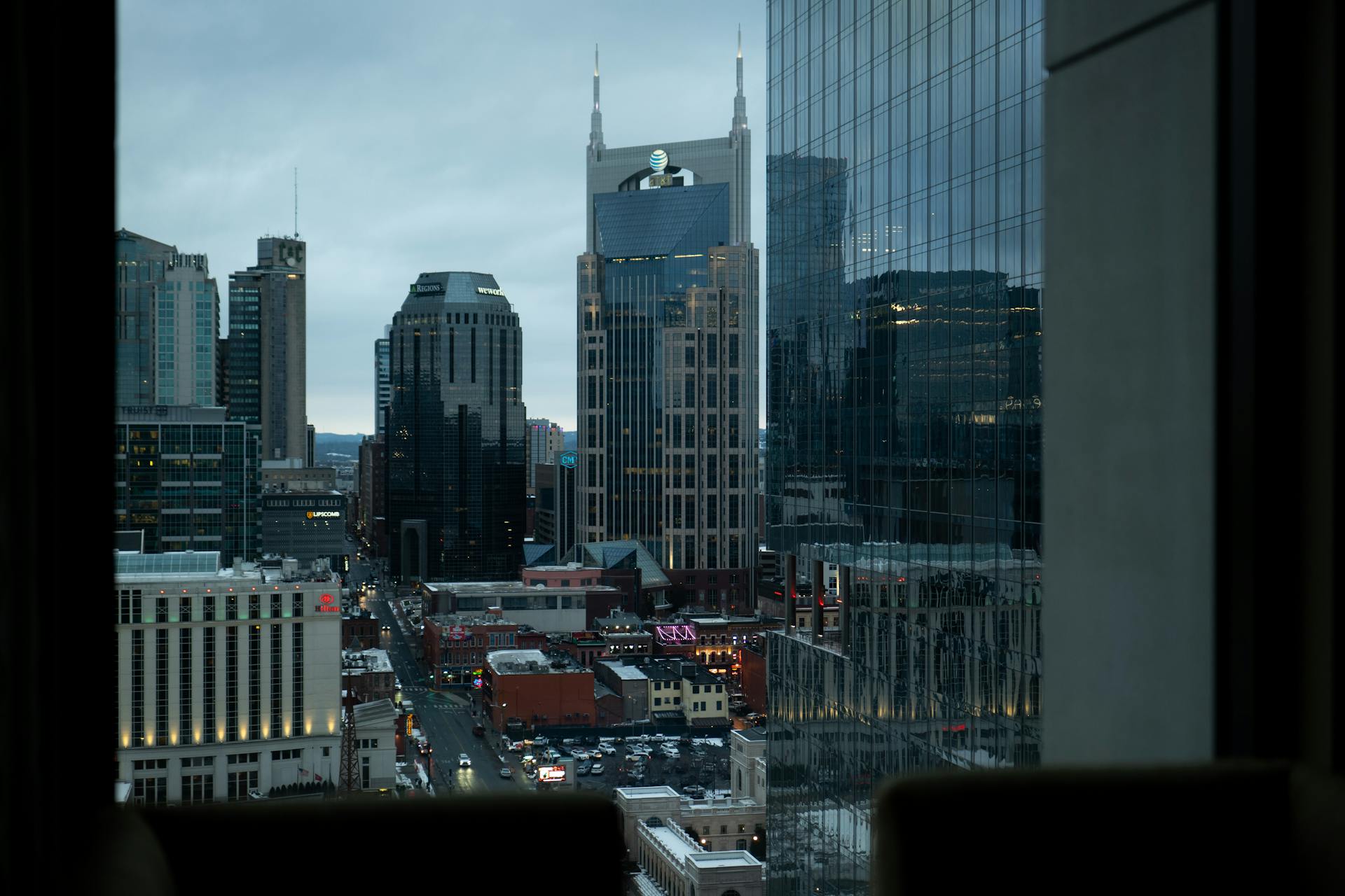 Downtown Nashville skyline with modern skyscrapers and historic buildings under a cloudy sky.