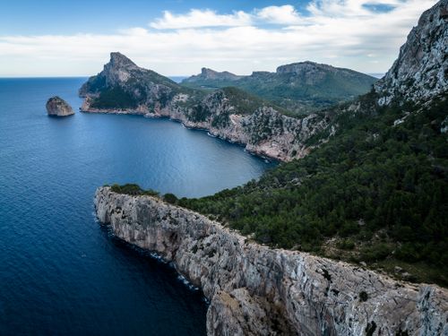 Free A breathtaking aerial view of a rugged coastline with blue ocean and lush greenery. Stock Photo