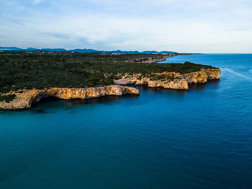 Aerial view of a rocky coastline meeting turquoise water — photo by Artem Zhukov on Pexels