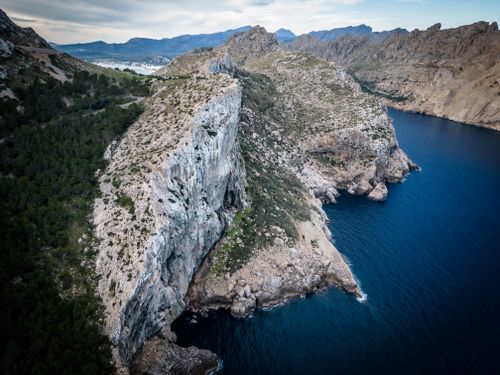 Free Aerial view of majestic cliffs beside a vibrant blue sea, showcasing nature's raw beauty. Stock Photo
