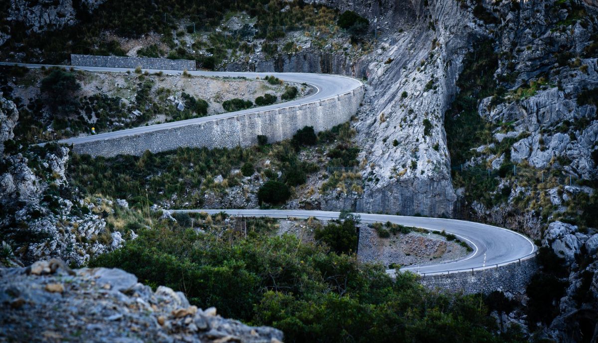 Winding serpentine mountain road with tight switchbacks, where controlled speed is essential when towing a trailer downhill