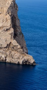 A breathtaking view of a towering rock formation meeting the calm blue ocean waters.