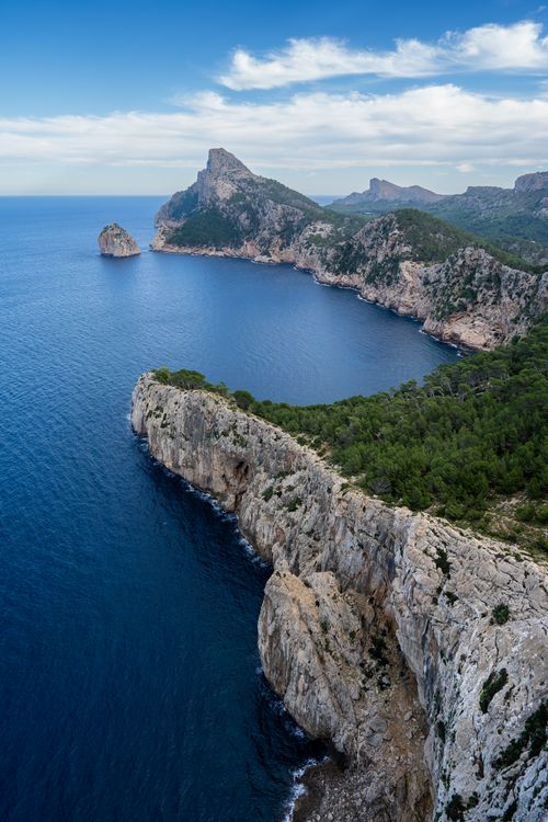 Free Breathtaking aerial scenery of rugged cliffs and calm sea under a clear blue sky. Stock Photo