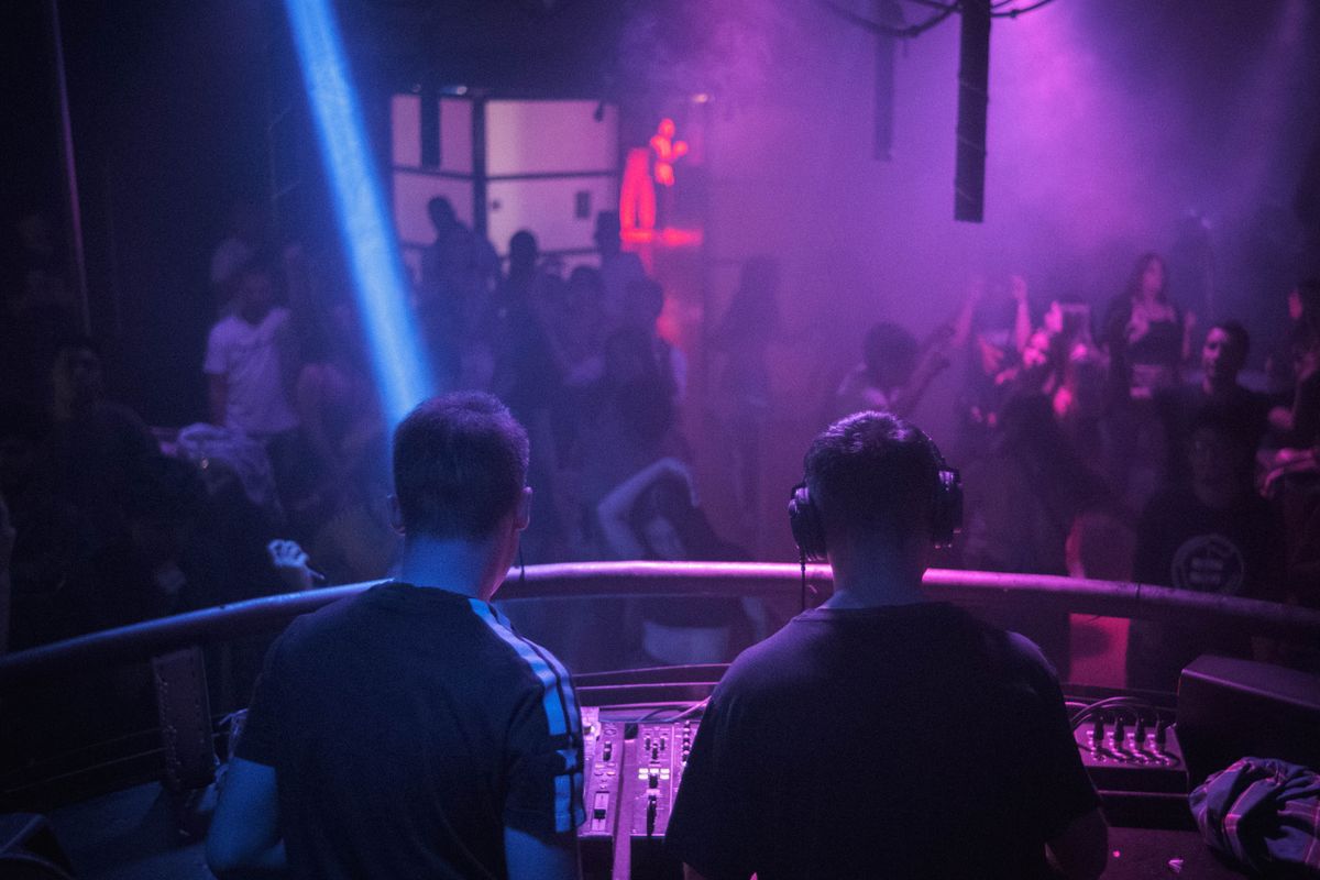 Italian nightclub interior with DJ booth lighting effects and crowd dancing