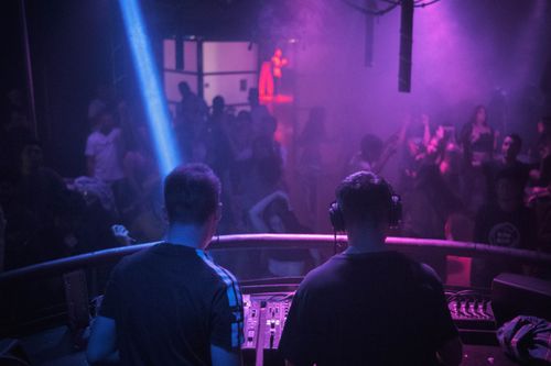 Free A lively night club scene with a DJ mixing music amidst vibrant lights and dancing crowd. Stock Photo