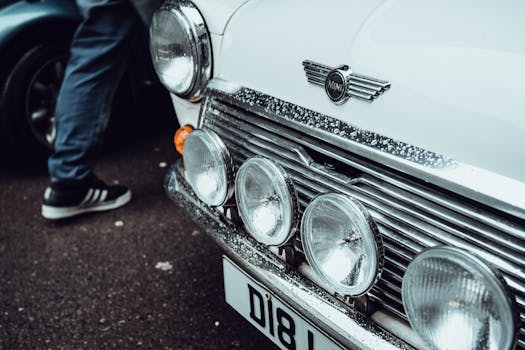 Close-up of a classic Mini Cooper showing the front with headlights and raindrops on the hood.