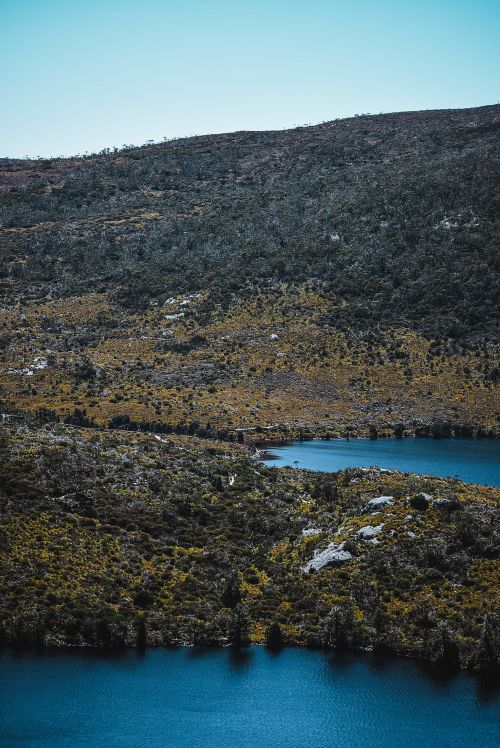 Free Breathtaking aerial view of a rugged landscape with a blue lake amidst rolling hills. Stock Photo
