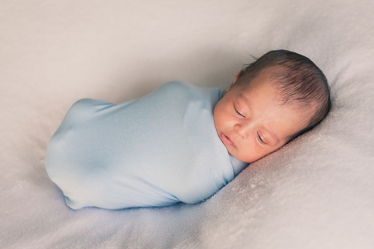 Peaceful newborn baby sleeping snugly in a soft wearable sleep sack