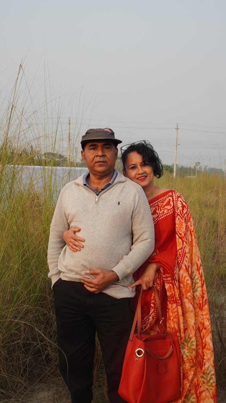 A Woman In A Saree Hugging A Man In A Gray Sweater