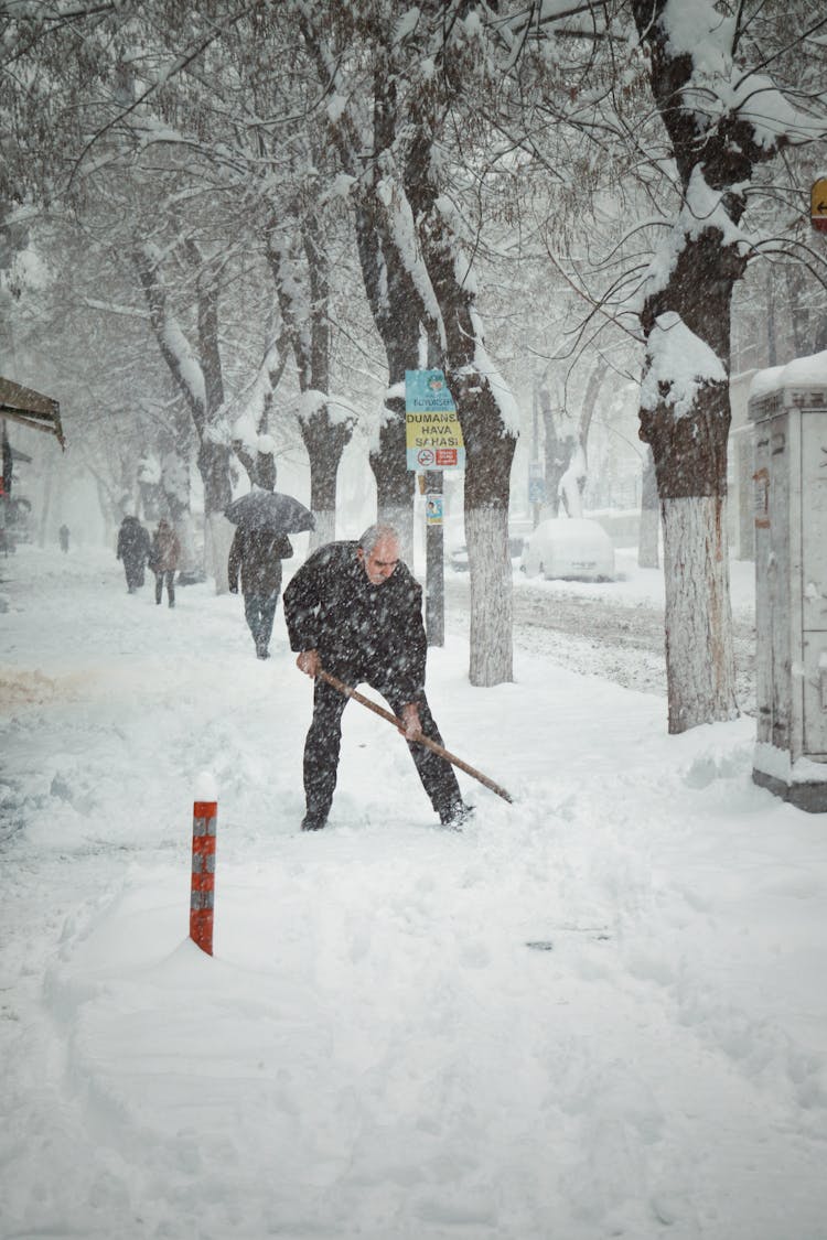 A Man Shoveling The Snow On The Street