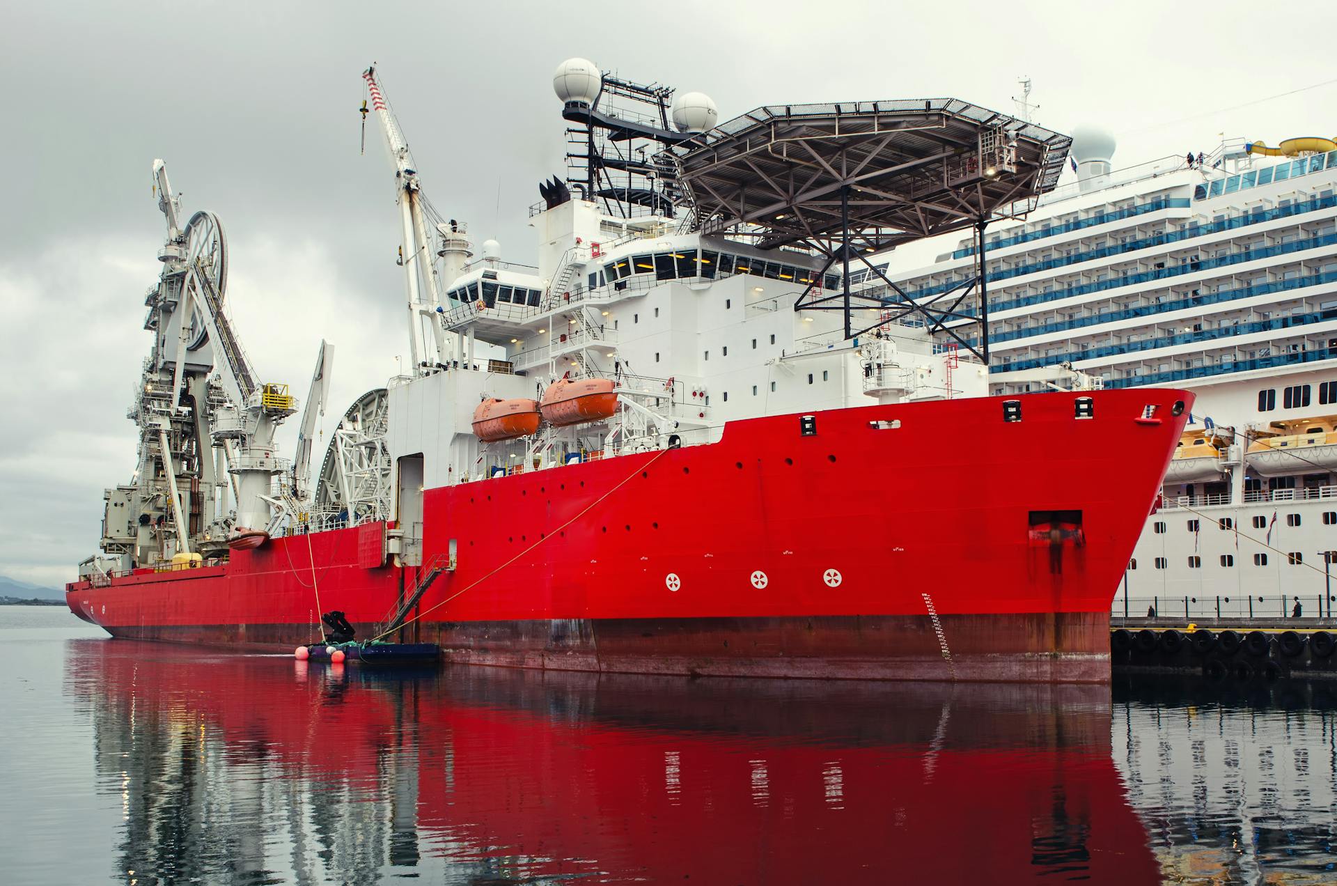 Imposing red cargo ship and oil tanker docked at Alesund harbor, Norway.