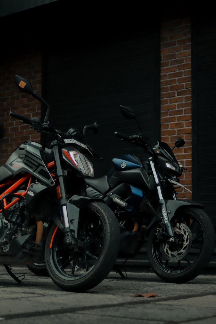 Motorbikes Parked Beside A Brick Wall