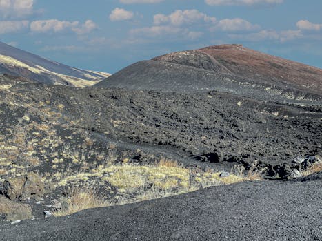 Dramatic view of Mount Etna's volcanic terrain with contrasting textures and colors under a clear sky.