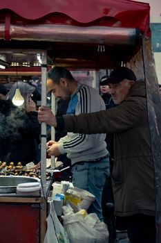 A street vendor sells roasted chestnuts at an outdoor food stall during a winter festival.