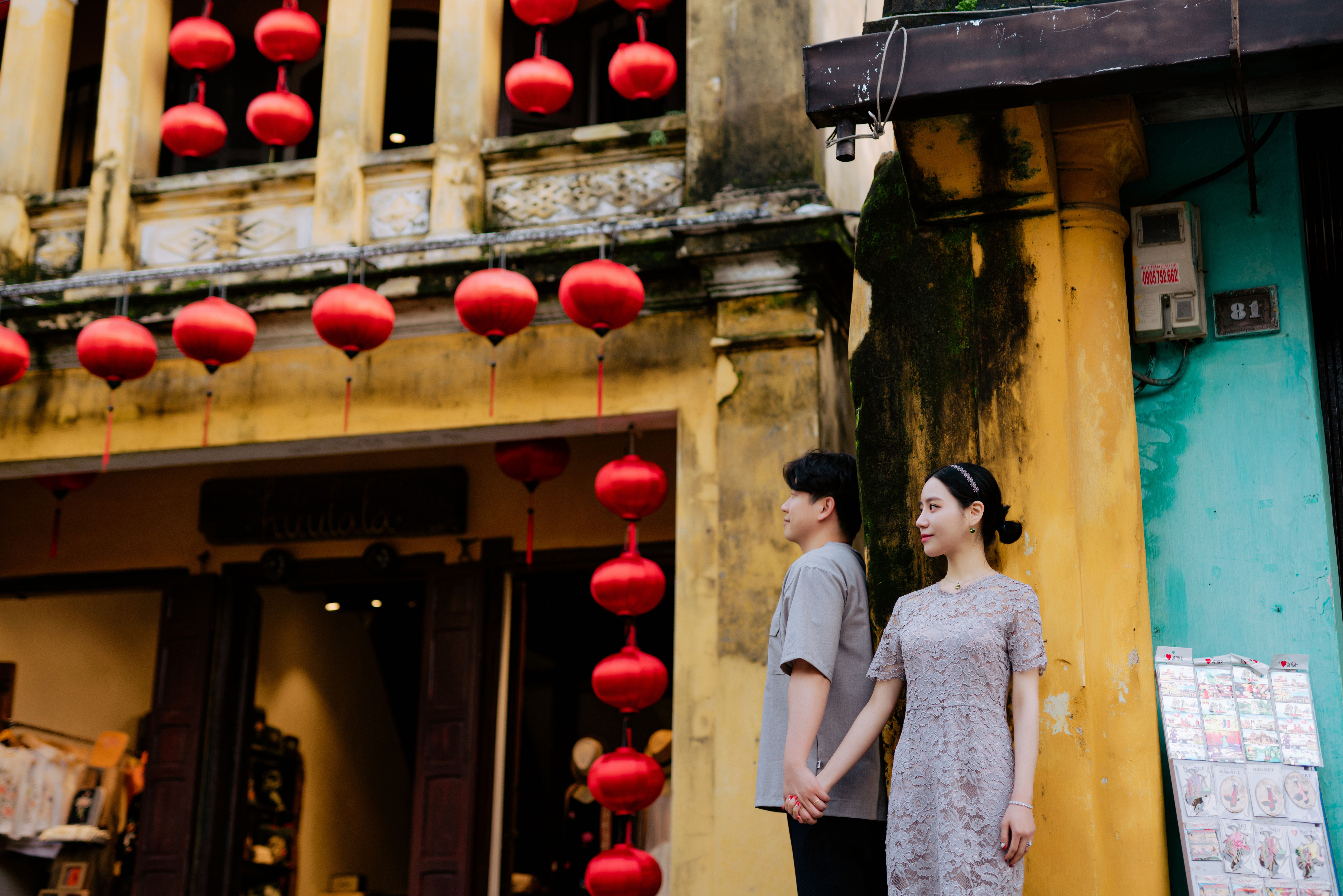 An Asian couple holding hands with romantic red lanterns in the background, depicting love and cultural charm.