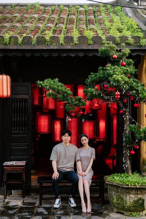 Couple Sitting on a Wooden Bench beside a Potted Plant