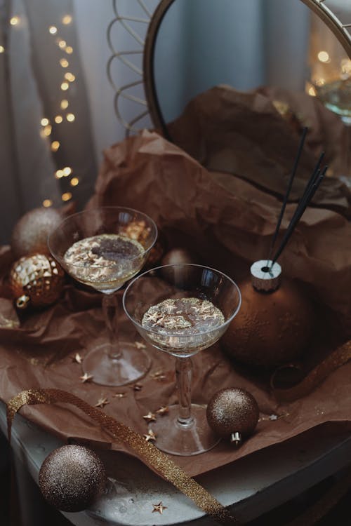 Champagne Glasses with Glitter on Table Cluttered with Christmas Ornaments