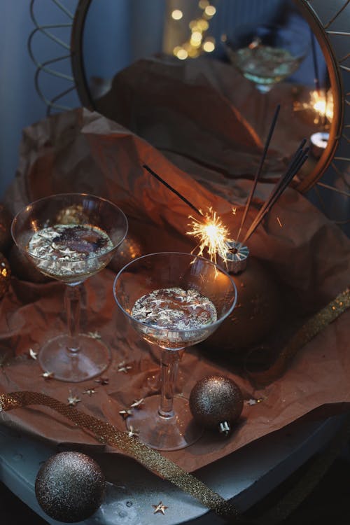 Glasses with Water and Glitter on Table by Mirror