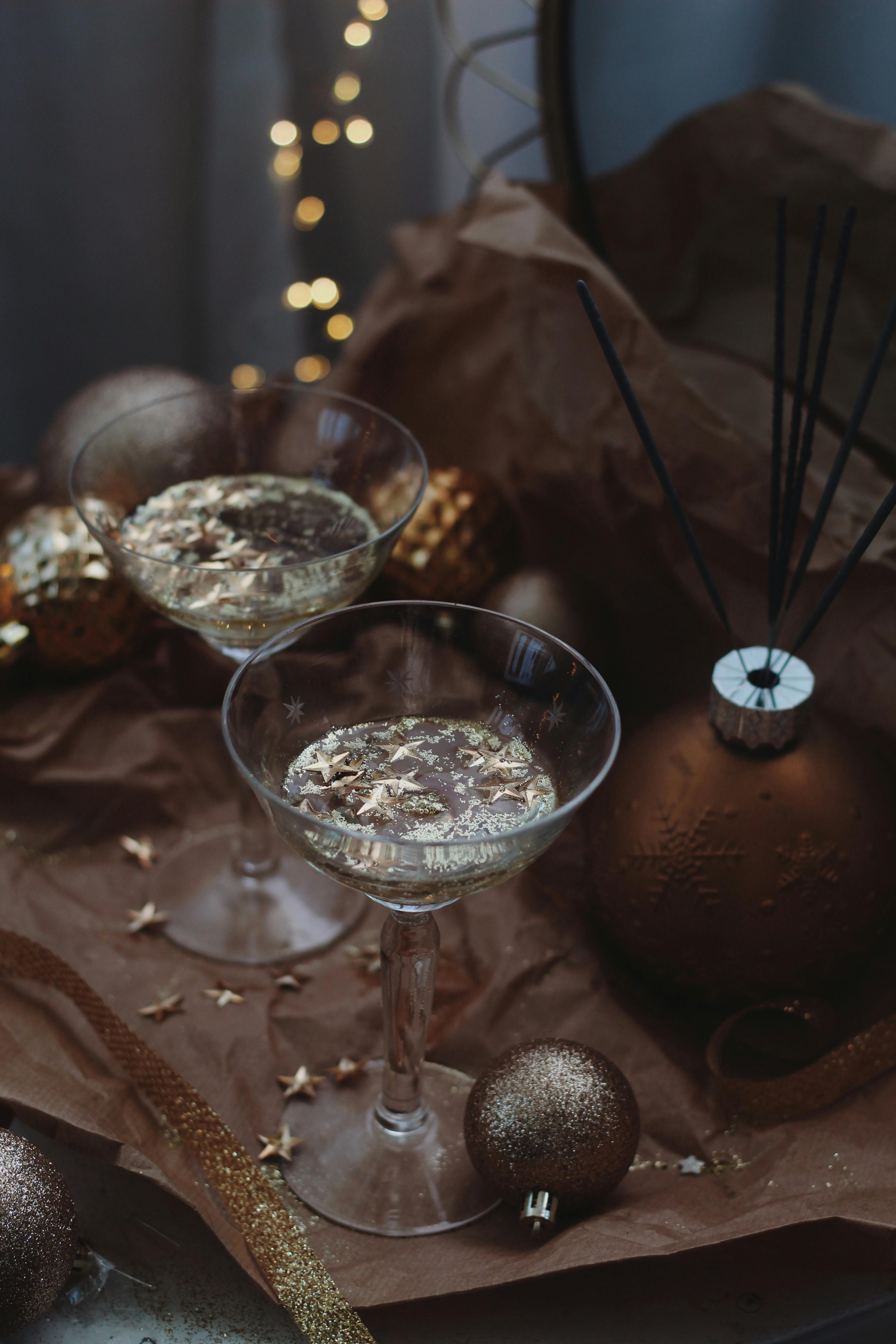 Two champagne glasses with gold decorations surrounded by festive ornaments perfect for a holiday celebration.