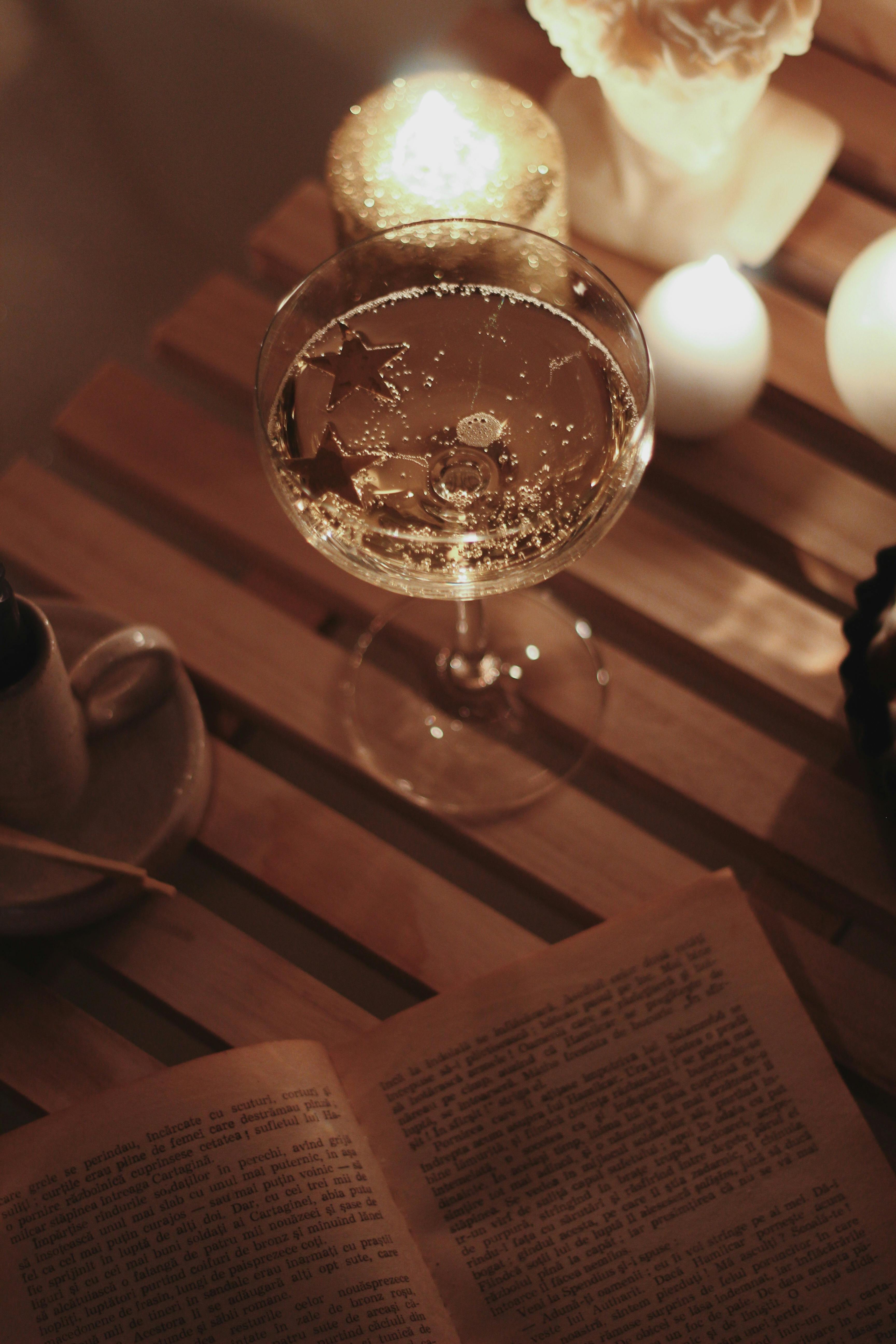 Elegant champagne glass on a wooden table with glowing candlelight for a serene evening.