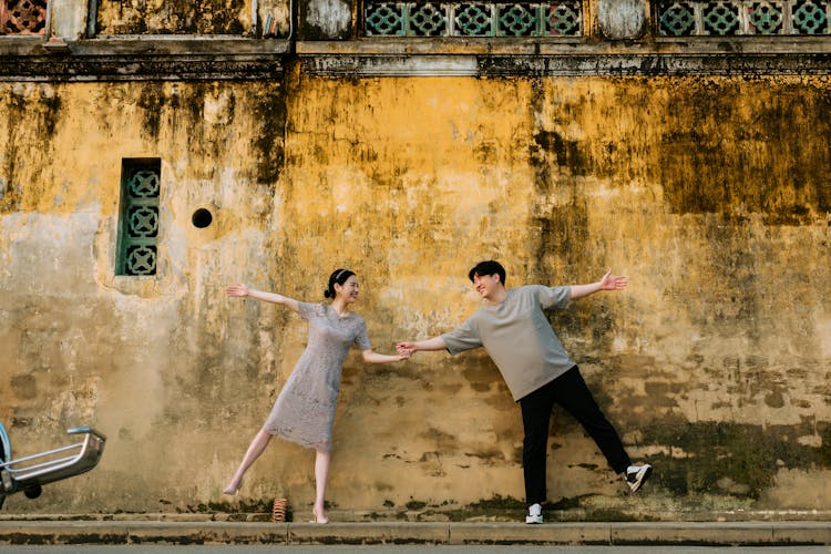 A Couple Posing In Front Of A Stained Wall