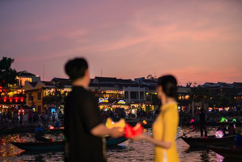 Couple Standing on River Bank in City at Sunset