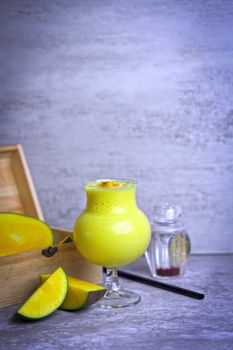 Delicious mango smoothie in a glass with fresh mango slices, perfect for a refreshing treat.