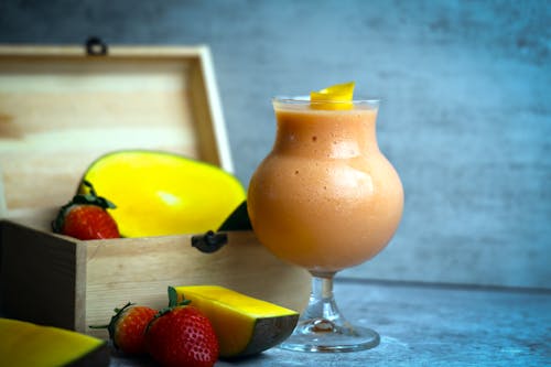 A smoothie with strawberries and mangoes in a glass