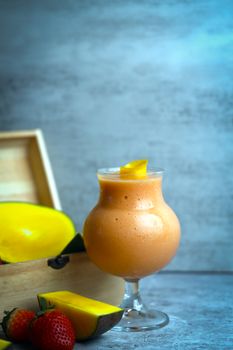 Delicious mango smoothie in a glass with fresh fruits on the side, perfect for a healthy lifestyle.