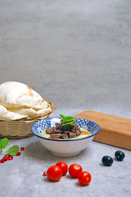 Free Delicious Mediterranean meal with pita bread and fresh vegetables served on a rustic table. Stock Photo