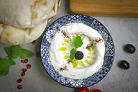 Delicious creamy labneh topped with olive, mint, and olive oil, served with flatbread.