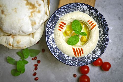 Free A fresh plate of hummus served with warm pita bread, cherry tomatoes, and mint garnish. Stock Photo