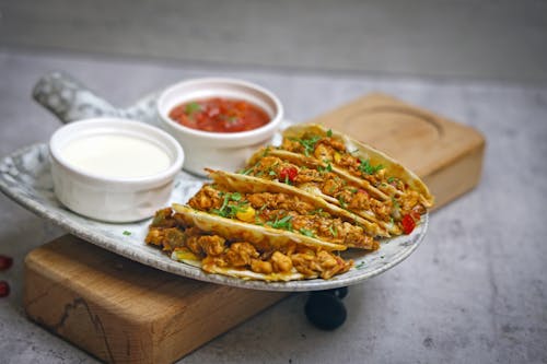 A plate with two tacos and a bowl of sauce