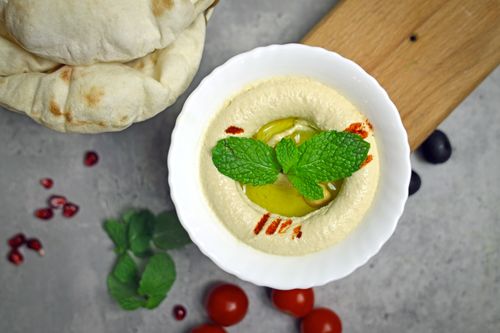 Free A bowl of creamy hummus garnished with fresh mint leaves, served with pita bread. Stock Photo