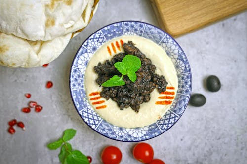 A bowl of hummus with pita and tomatoes